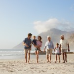 Multi Generation Family On Vacation Walking Along Beach Together